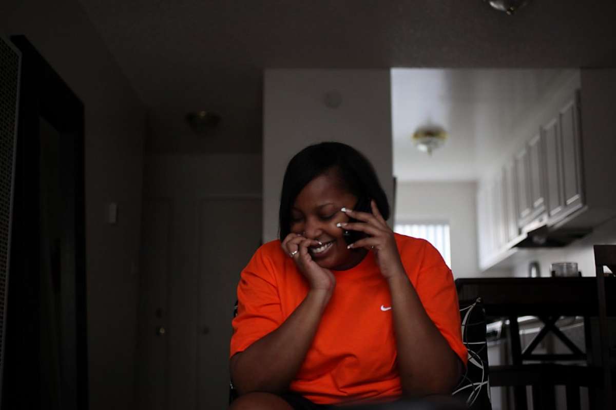 Woman on phone laughs while sitting in living room.