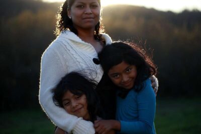 Mother with two children pose for photo in front of sunset.