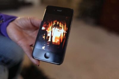 Close up of a smartphone showing photo of a wild fire.