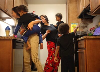 Family of five cooks together in modest kitchen.