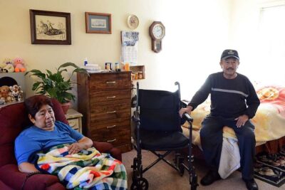 Elderly couple sitting in bedroom.