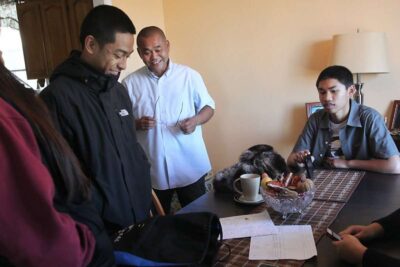 Family enjoys company around kitchen table.