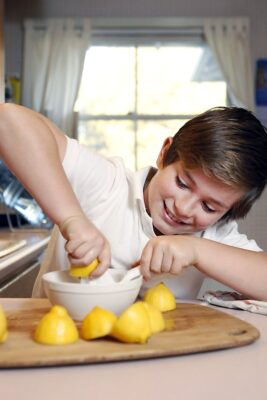Child making homemade lemonade in kitchen.