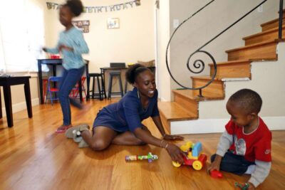Family of three play on the floor of living room.