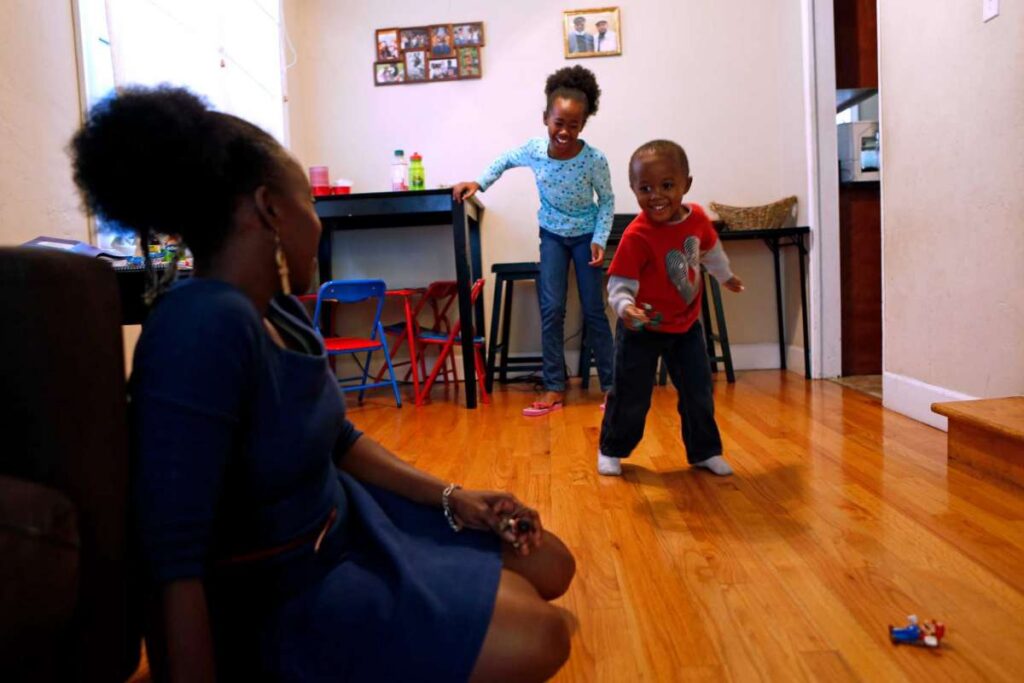 Mother watching children play in their living room.