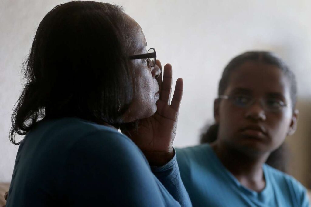Woman wiping away tear while daughter supports her.