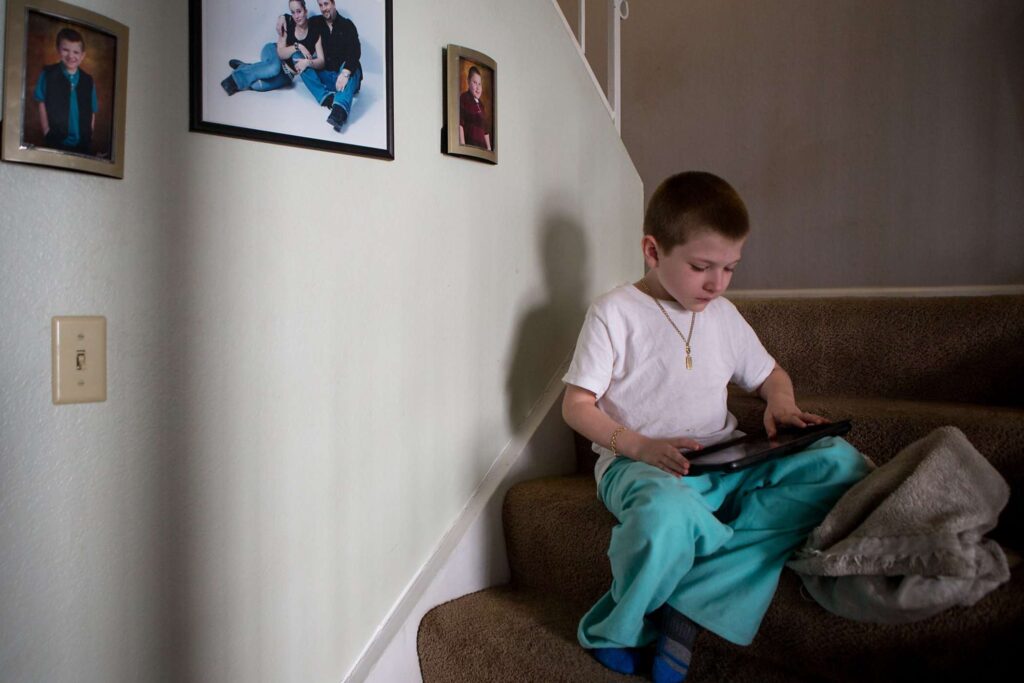 Child plays game on tablet while sitting on stairs.
