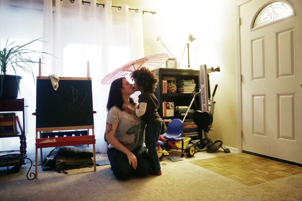 Mother kisses son in living room.