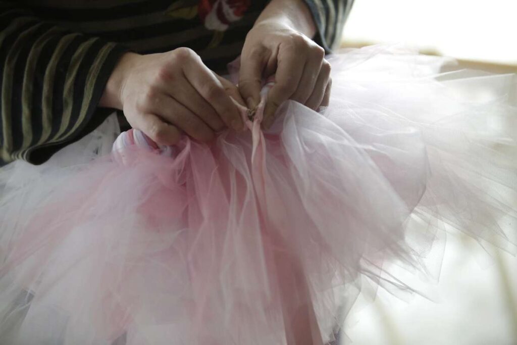 Close up of hands sewing a ballerina tutu.