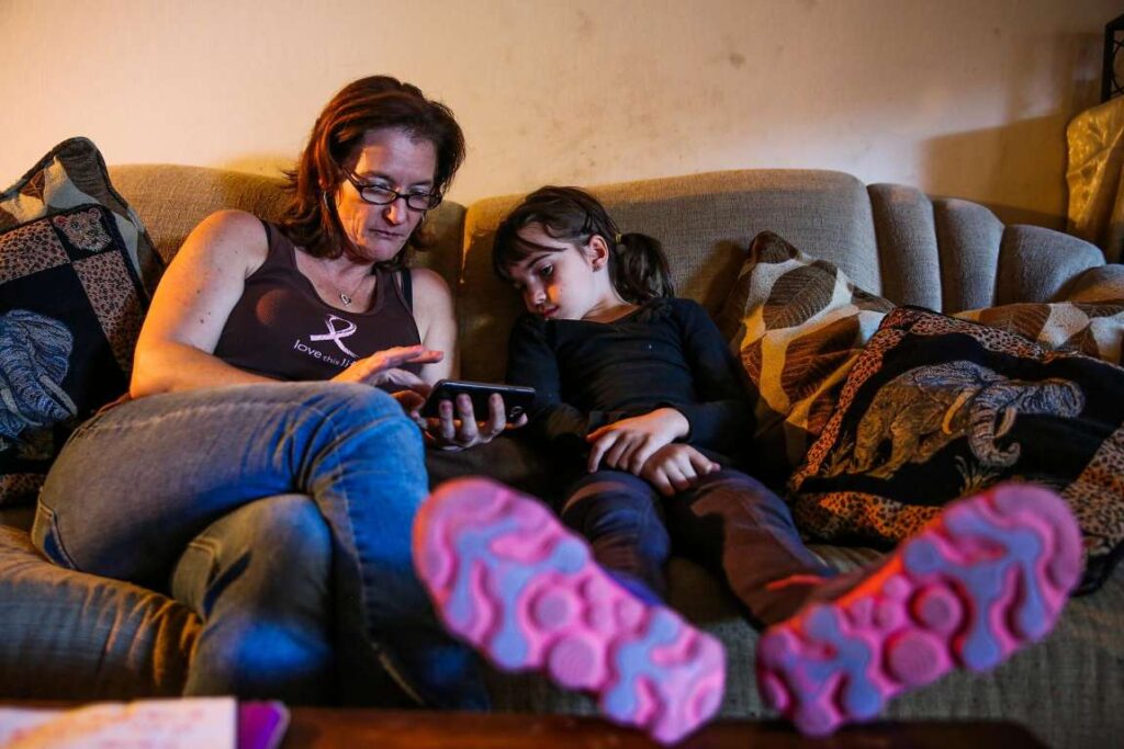 Adult and child sitting on the couch in pajamas.