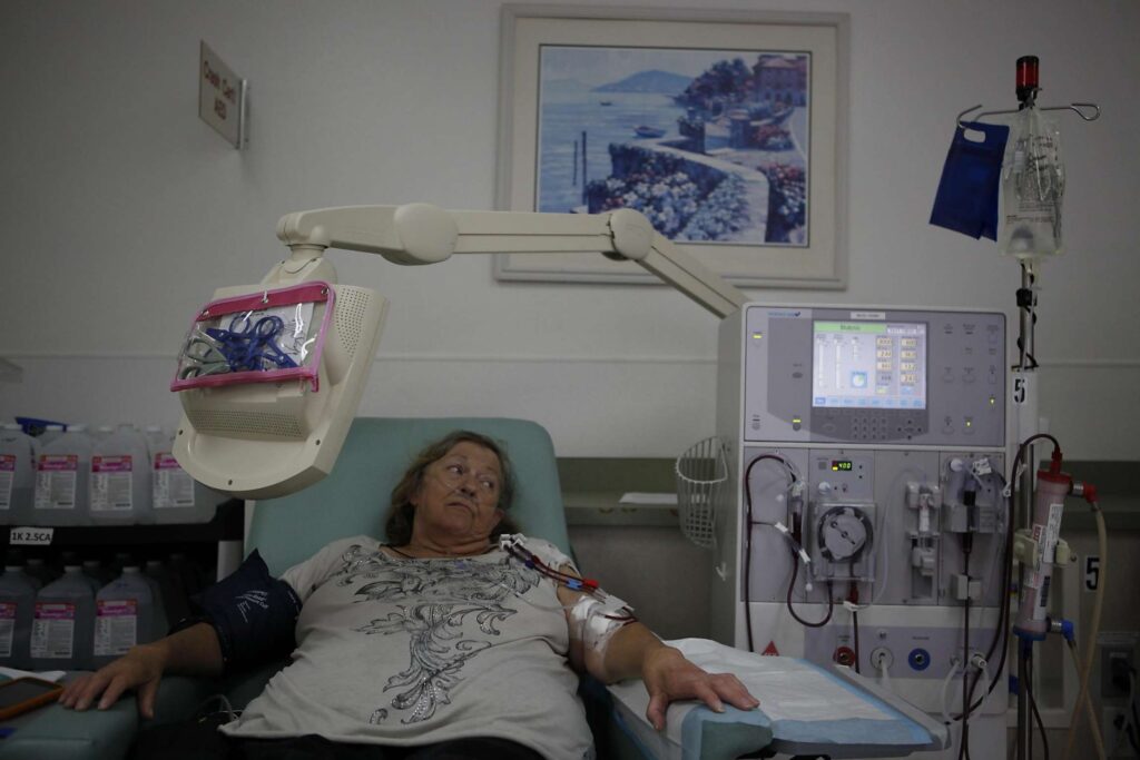 Woman in hospital bed next to medical equipment.