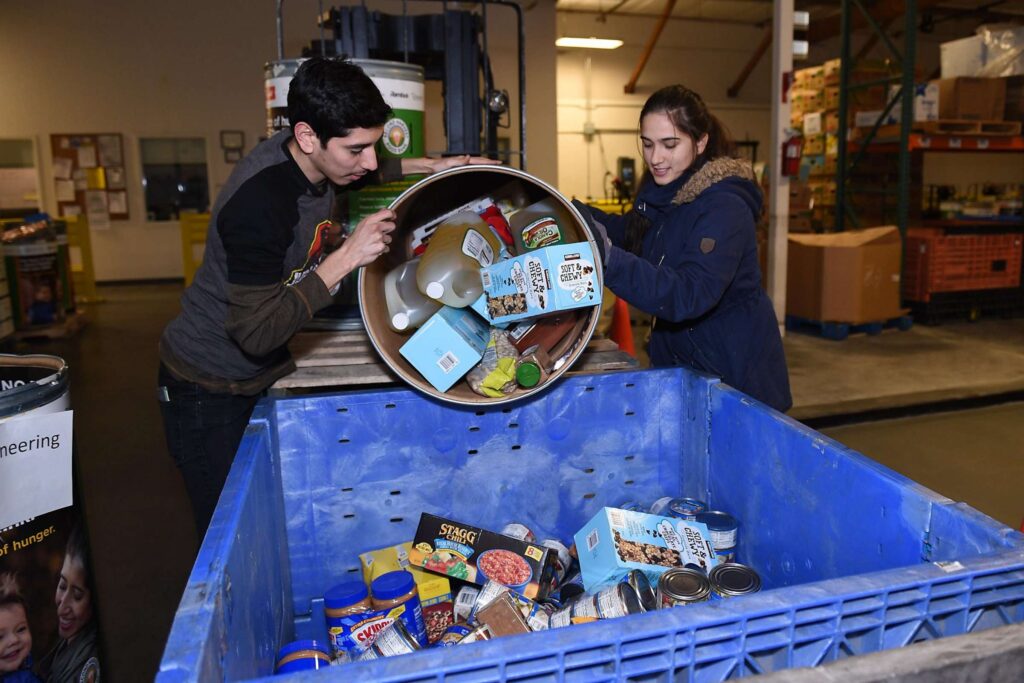 Volunteers sorting canned goods into blue bins.