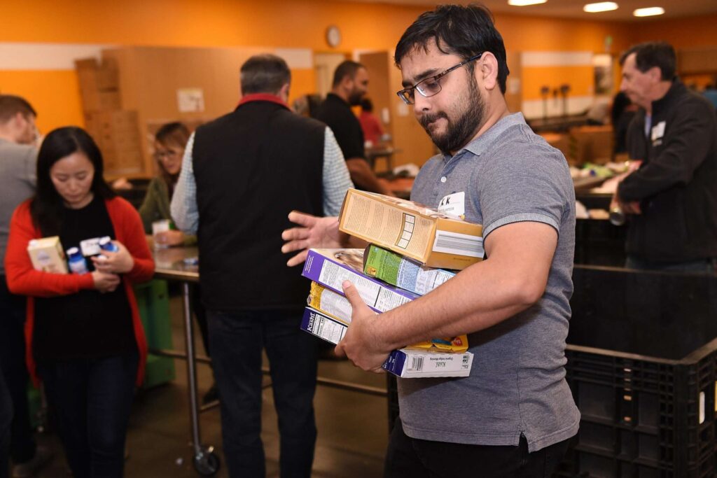 Volunteer holding several boxes of dry cereal at a food pantry.