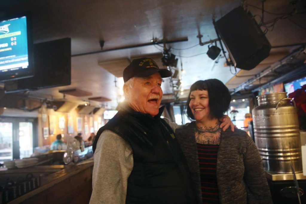 Elderly man greets friend at restaurant.