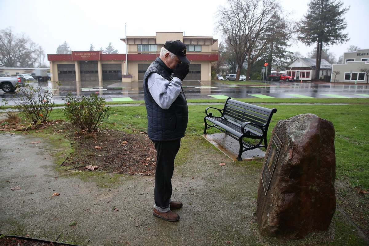 Man stands near park bench on foggy day.
