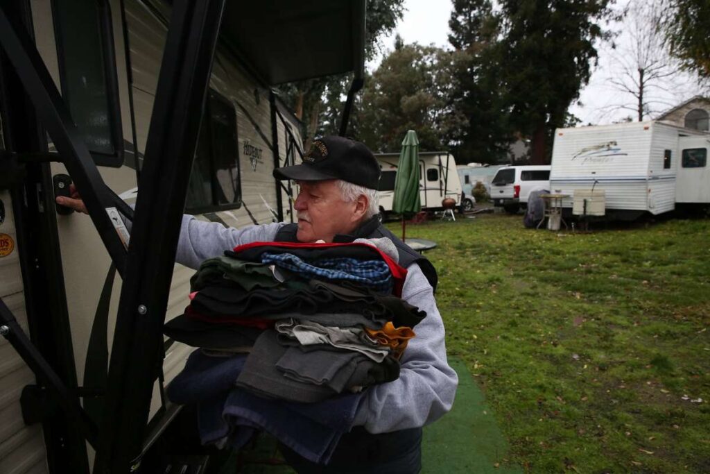 Man bringing folded clothes into his trailer.