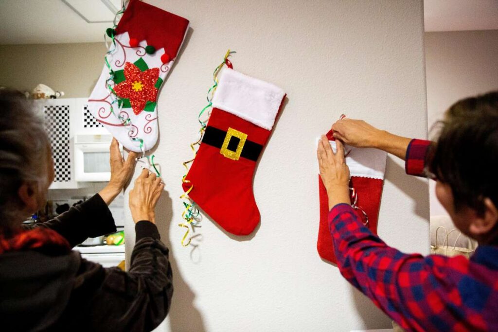 Family hanging stockings for Christmas on wall.