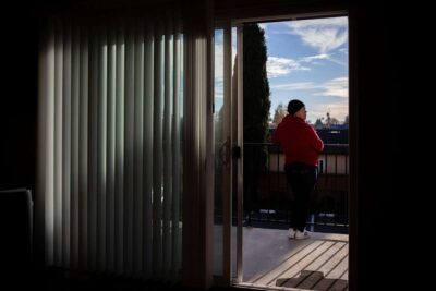 Woman stands on apartment balcony looking at view of nature.