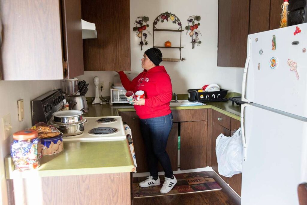 Woman prepares coffee at a kitchen sink in a holiday-decorated room.