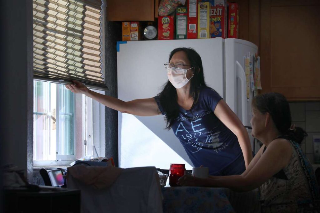 Woman draws blinds in a kitchen window.