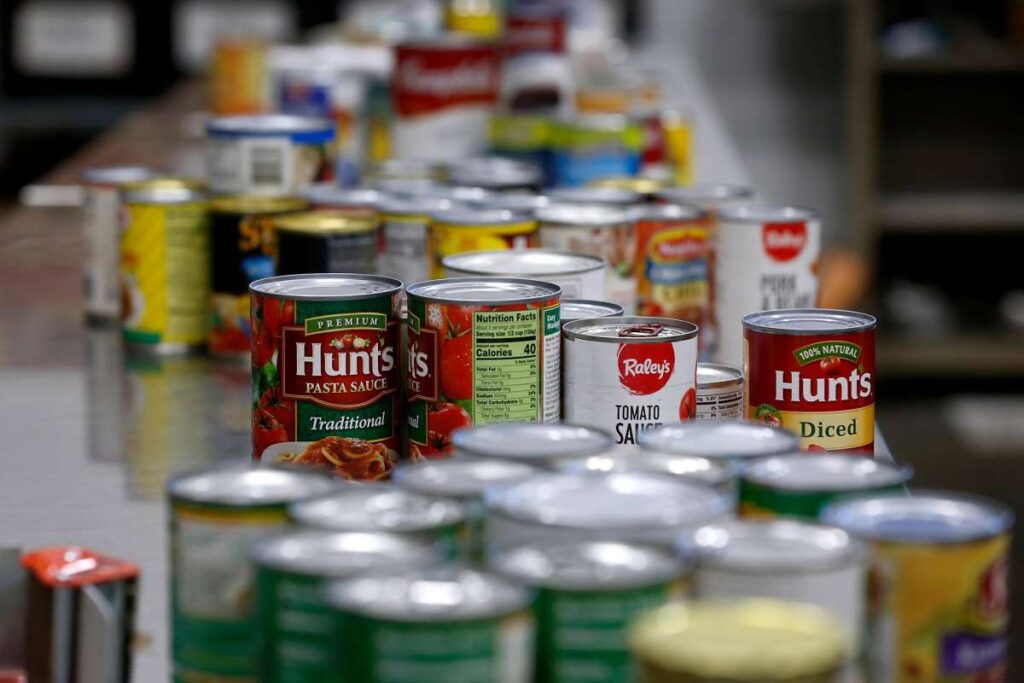 Close-up of canned food, including Hunt’s tomatoes, stacked for distribution.