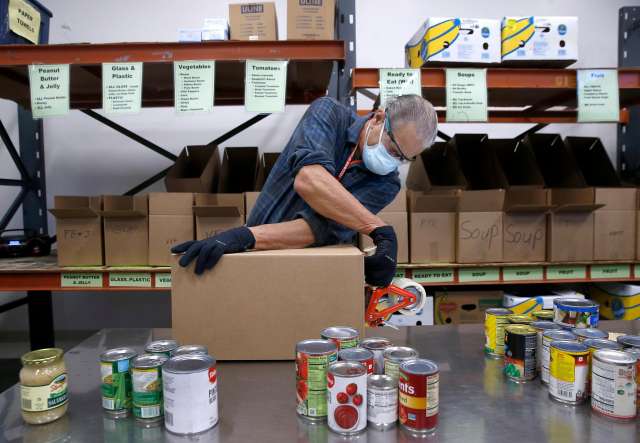 Volunteers sorting donations and packaging boxes in a warehouse.