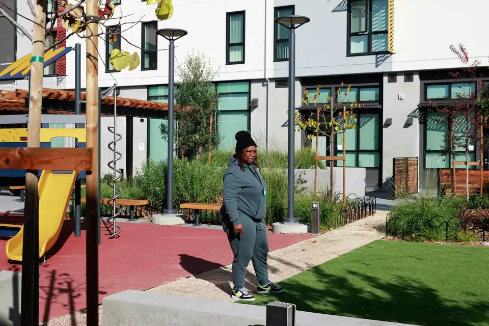 Woman walking past modern apartment buildings.