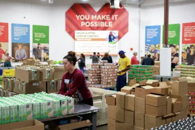 Volunteers organize food boxes under a sign that reads “You Make It Possible”—showing gratitude and teamwork.