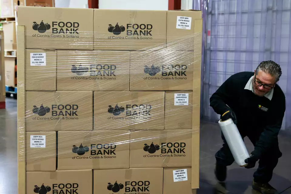 Stacks of boxes labeled “Food Bank” in a warehouse—signifying large-scale donation efforts.