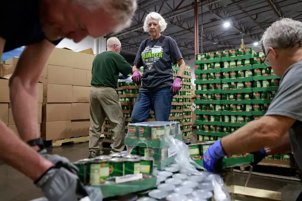 Volunteers sort cans in a food bank warehouse—emphasizing efficiency and shared mission.