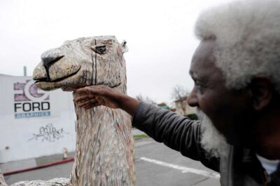Close up of hand touching wooden sculpture art piece of a camel.