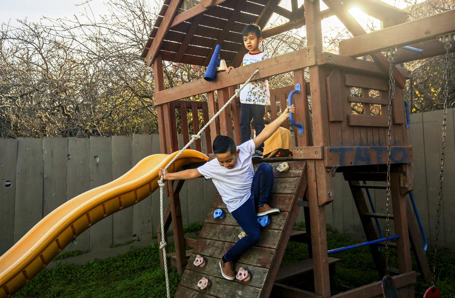 Children play on a wooden jungle gym in a yard—representing energy, outdoor fun, and safe space.