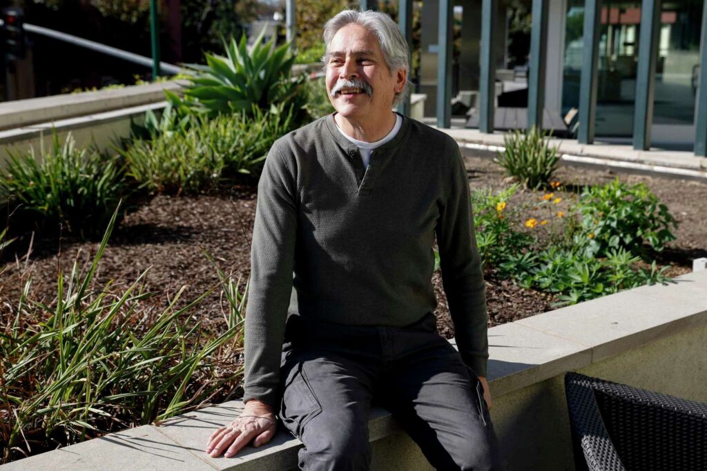Man smiling in a garden—emphasizing nature and healing spaces.