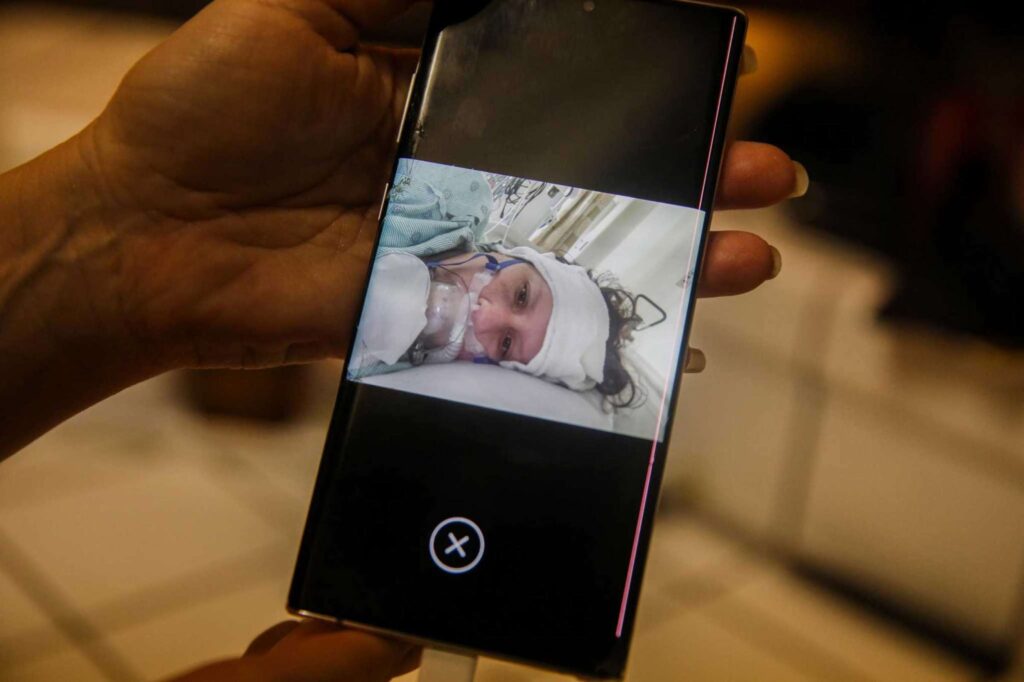 A smartphone screen displays a woman in hospital bed—emphasizing resilience and strength.
