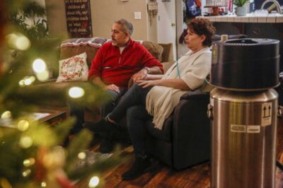 A man and woman sit on a couch during the holidays, holding hands—showcasing togetherness and joy.