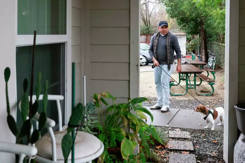 Man walking on a garden path beside a house.