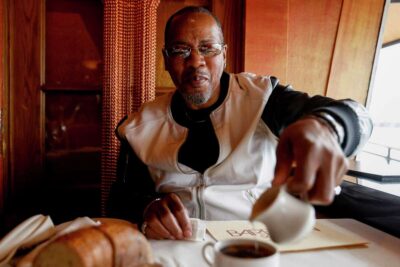 A man prepares coffee at a table in warm lighting—capturing culture and routine.