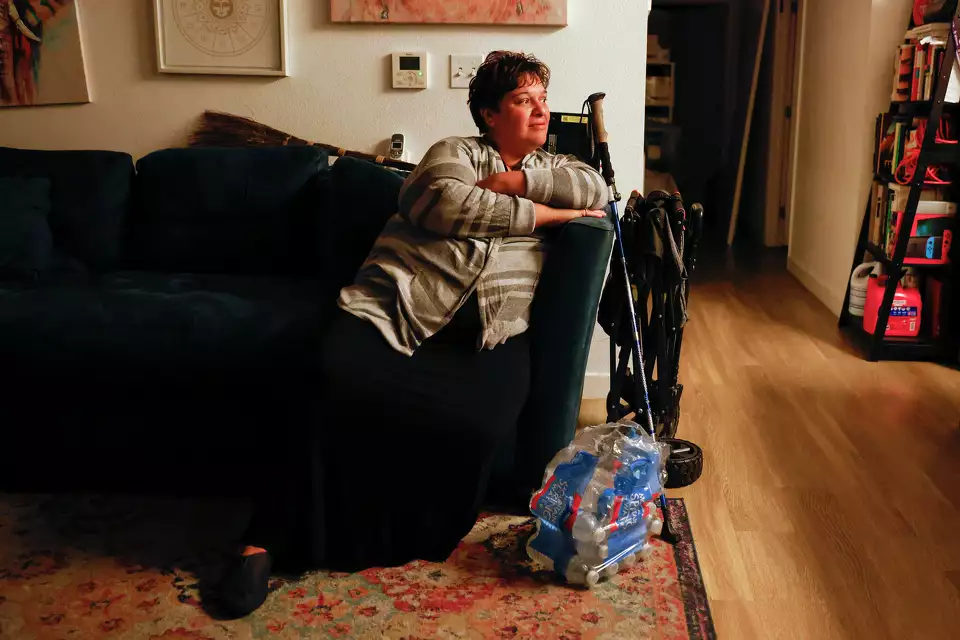 A woman reclines in a living room with a cane and walker beside her—portraying rest and resilience in daily life.