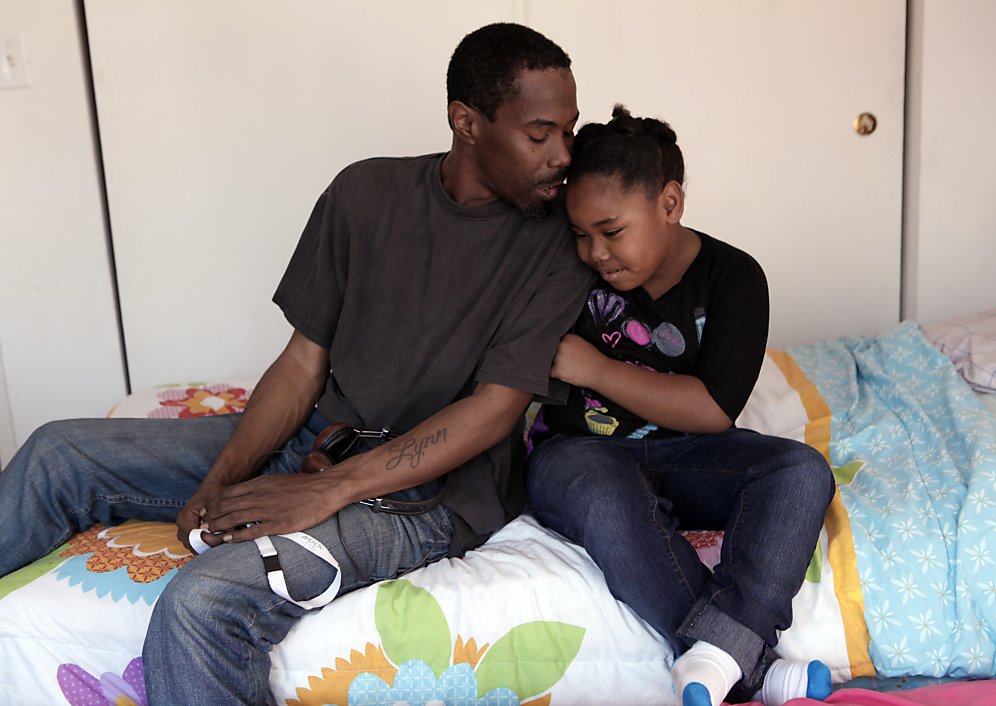 Man and daughter cuddle affectionately on bed.