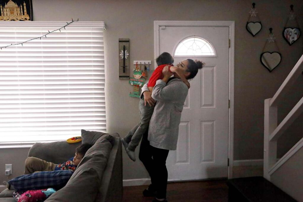 Woman holds her son in a living room.