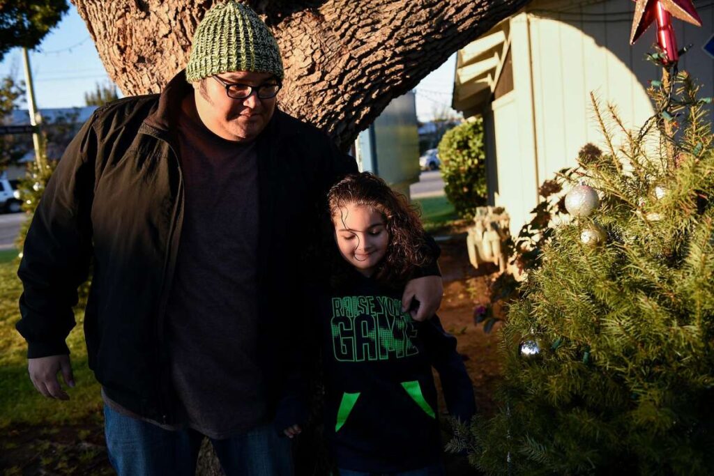 Man and child walking outdoors near holiday decorations.