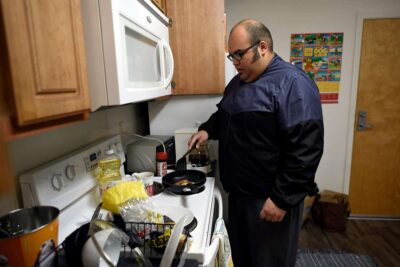 Man cooking on a stovetop in a compact kitchen space.