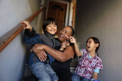 Family of three laughing together on stairway.