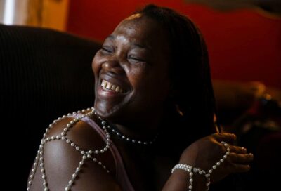 A woman in a beaded dress laughs freely in warm light—capturing joy and self-expression.