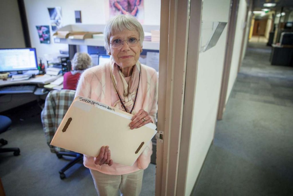 Woman carrying a folder and smiling in a community office.