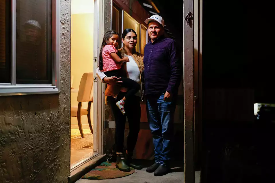 A couple and their child standing in a warm hallway—representing hospitality and inclusion.