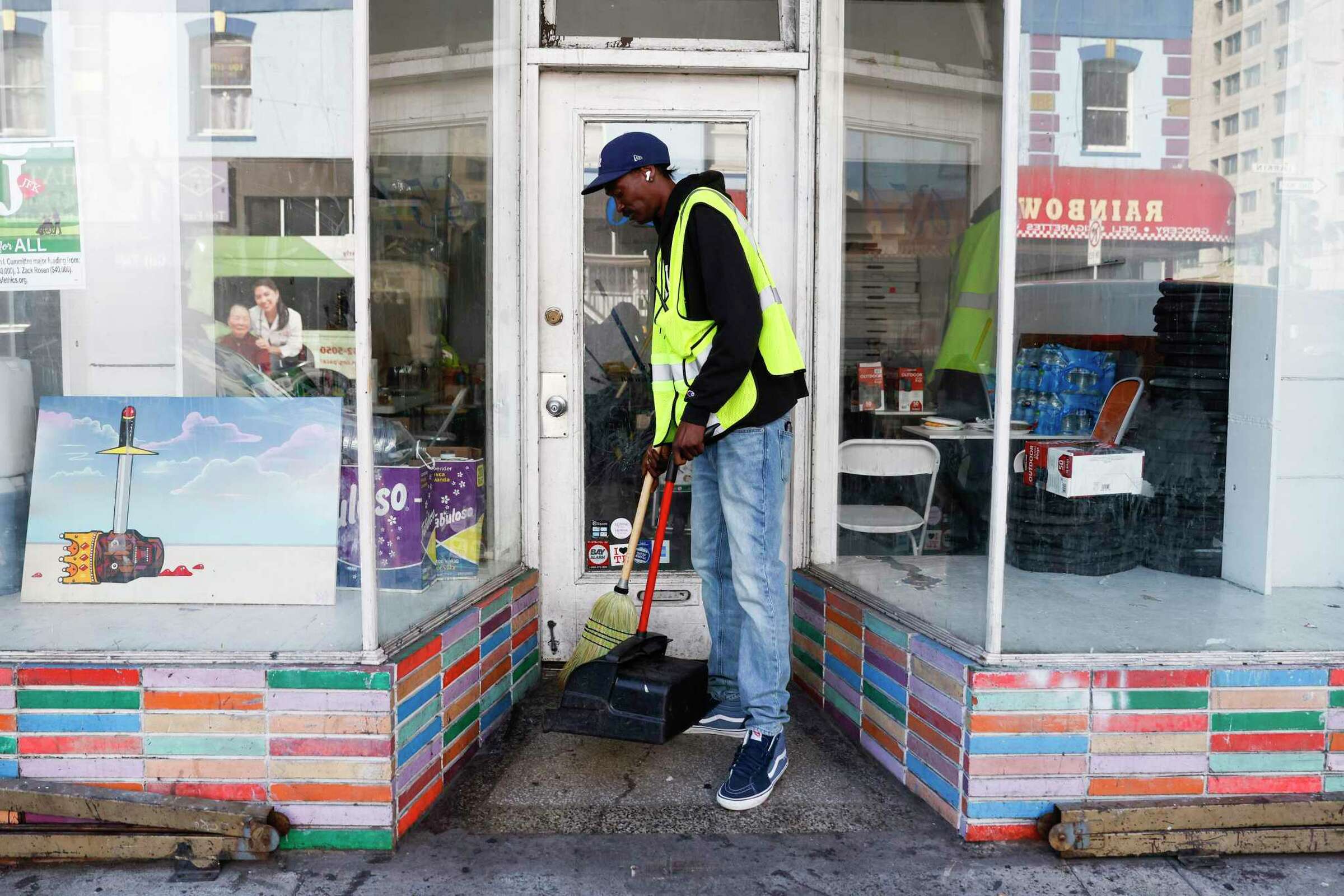 A man sweeps outside a storefront—suggesting dedication and community upkeep.