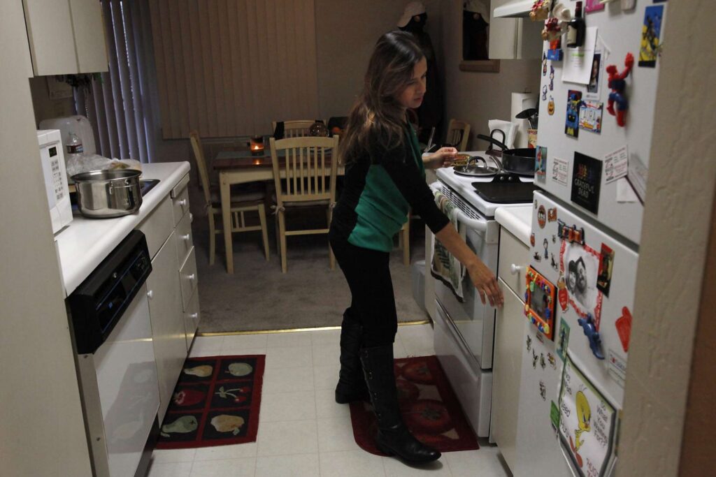 Woman prepares meal in modest kitchen.