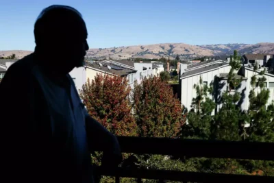 A man looks out over a scenic hillside from a balcony—evoking reflection and peace.