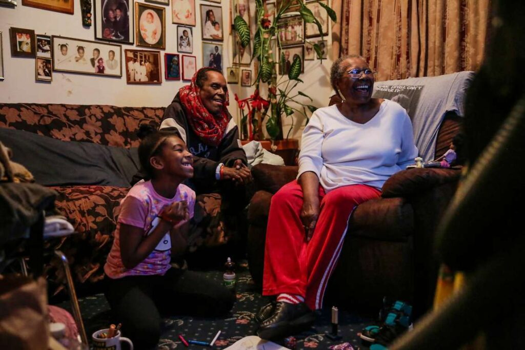 Family sitting on a couch in a living room, watching TV.